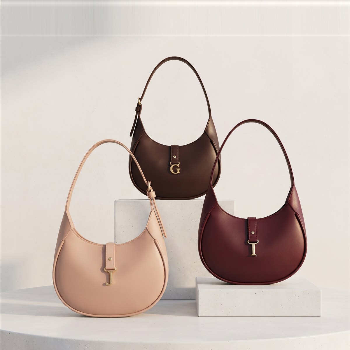 Elara: tres bolsas de hombro en media luna con letra dorada colgante en rosa nude, café y vino